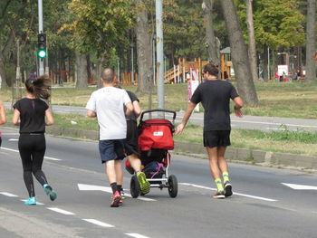 Rear view of people walking on road in city