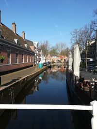 Canal amidst buildings in city against sky