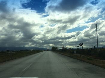 Empty road against cloudy sky