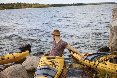 Man sitting on kayak on coast and looking away