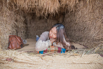 Young woman sleeping on mat in hut at village