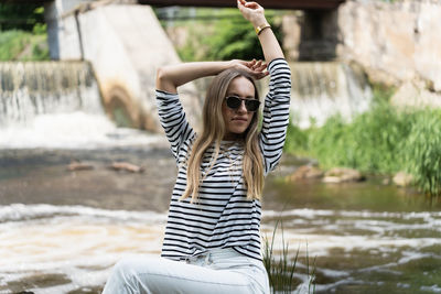 A woman relaxes and rests, sitting near the river in early summer