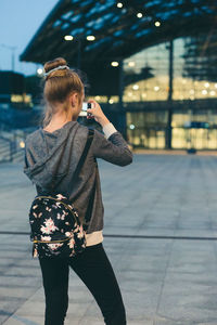 Woman photographing with umbrella standing on street in city