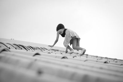 Low angle view of child on roof against sky