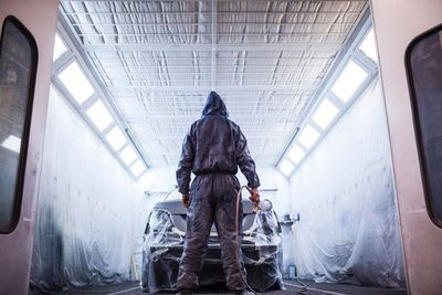 Rear view of man spray painting car