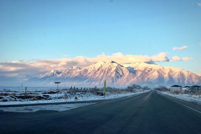 Road by mountains against sky during winter