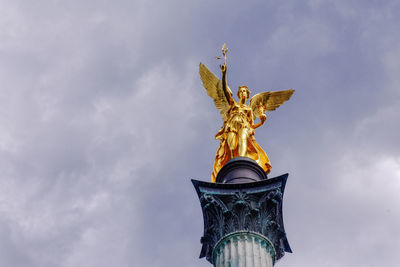 Low angle view of angel statue against cloudy sky