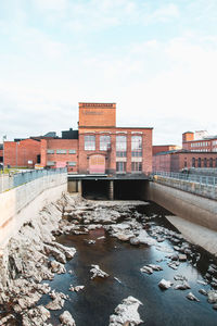 Bridge over river amidst buildings against sky