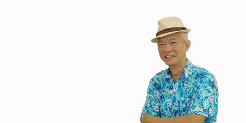 Portrait of smiling young man wearing hat standing against white background