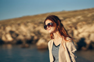 Portrait of young woman wearing sunglasses standing outdoors