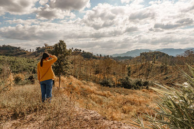 Rear view of man photographing against sky