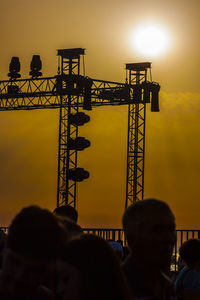 Silhouette people at construction site against sky during sunset