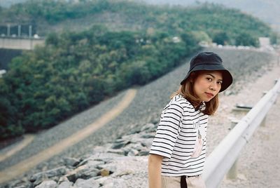 Young woman looking away while standing against trees
