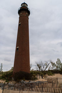 Low angle view of lighthouse by building against sky