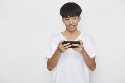 Smiling young man using mobile phone against white background