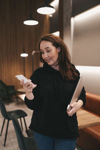 Adult confident business woman freelancer working in a coffee shop cafe using a laptop and phone