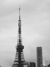 Communications tower in city against sky