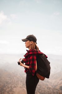 Full length of young woman standing on mountain against sky