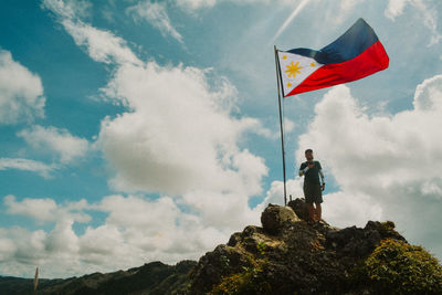 Low angle view of man standing on rock against sky