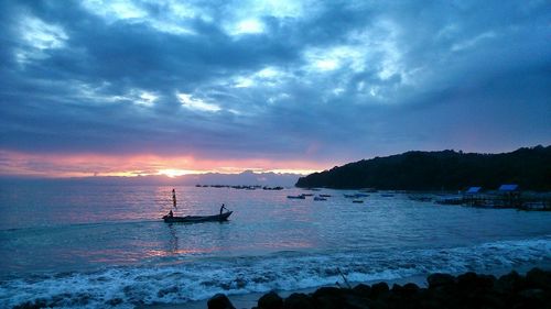 Silhouette sailboat in sea against sky during sunset