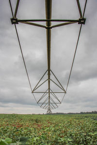 Low angle view of wind turbines on field against sky