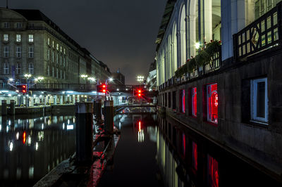 Alster canal amidst illuminated buildings in city at night
