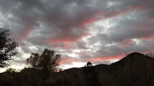 Low angle view of dramatic sky over silhouette landscape