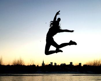 Silhouette of girl jumping at sunset