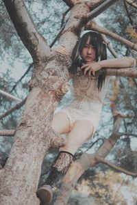 Portrait of woman by tree trunk