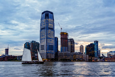 Sailing boat against skyline of hudson river waterfront of new jersey at sunset