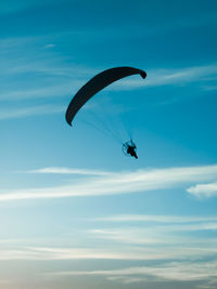 Low angle view of person paragliding against blue sky