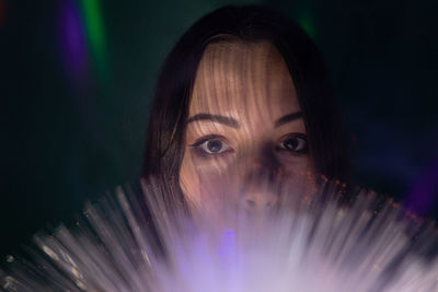 Close-up portrait of young woman holding multi colored fiber optic