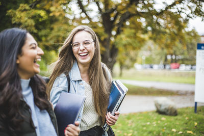 Portrait of smiling young woman standing against plants