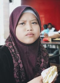 Close-up of girl wearing hijab eating fast food in restaurant