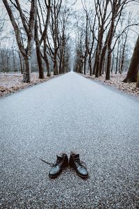 Shoes on road against bare trees