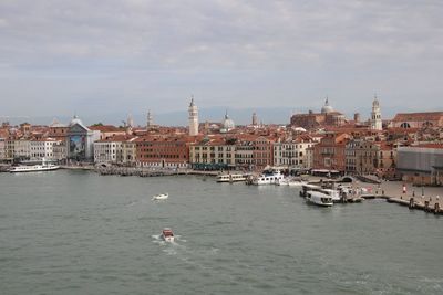 View of buildings at waterfront against cloudy sky