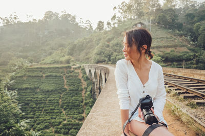 Woman with arms raised on landscape against trees