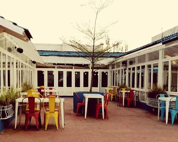 Chairs and tables at sidewalk cafe against clear sky