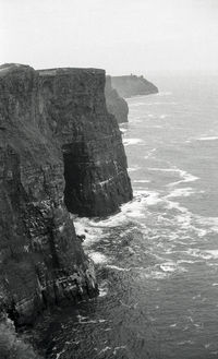 Rock formation by sea against sky