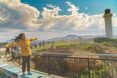 Rear view of woman standing by railing against sky