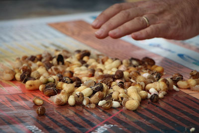 Cropped image of hand over peanuts on table