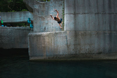 Full length of shirtless man jumping on wall