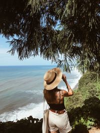 Rear view of woman standing by tree on beach