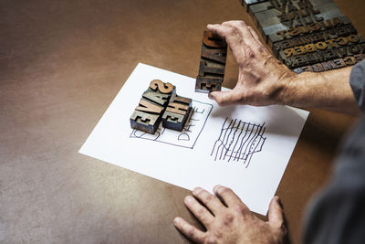 Cropped image of man holding letterpress wood in workshop