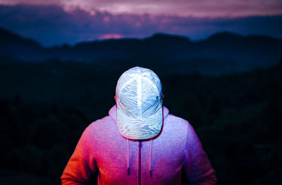 Rear view of man wearing mask against black background