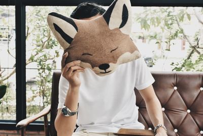 Man holding animal shaped cushion while sitting on sofa