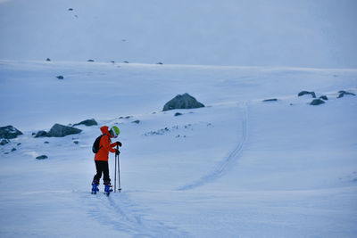 Rear view of person skiing on snow covered landscape against sky