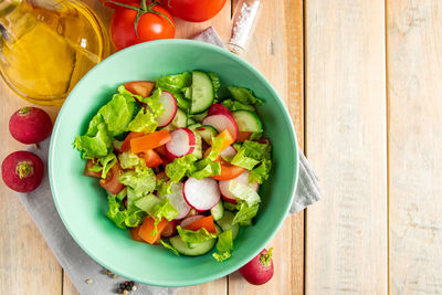 Fresh vegetable salad with olive oil in ceramic bowl on a wooden background 