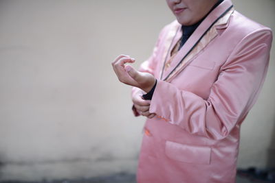Midsection of woman holding pink flower