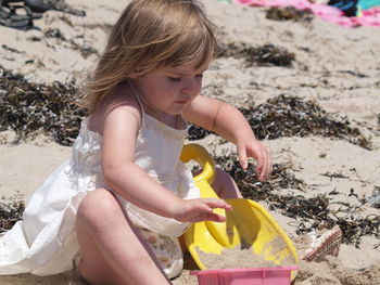 Full length of girl holding sand at beach